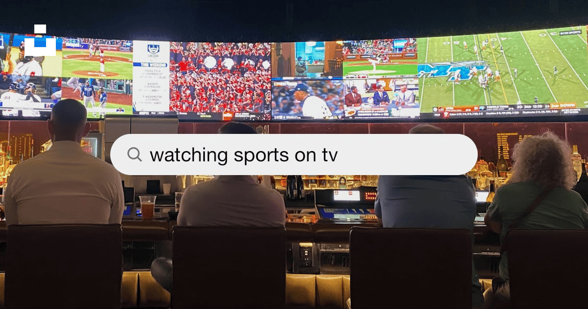 Smartphone on a table showing a sports score notification while a game plays on a blurred TV in the background