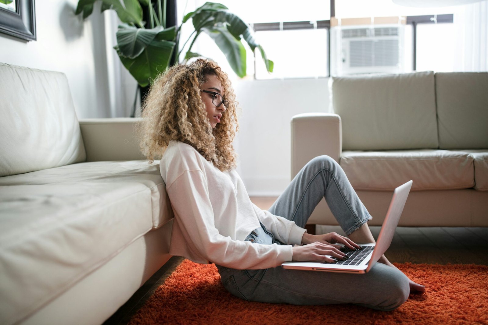 Person reviewing streaming account devices on a tablet with a TV, laptop and phone nearby, illustrating device management and account security.